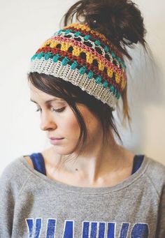 a woman wearing a gray shirt and a multicolored knitted beanie hat