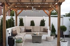 an outdoor living area with couches, tables and lights