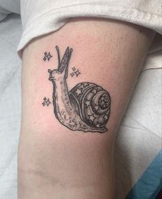 a small snail tattoo on the right side of the leg, with stars around it