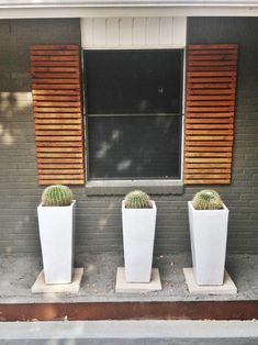 three large white planters sitting on the side of a building next to a window