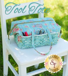 a blue floral purse sitting on top of a white chair with the words tool tote written above it