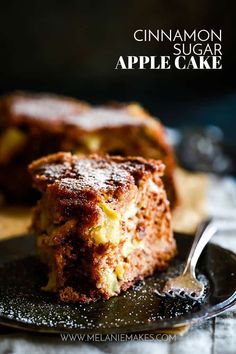 a piece of cinnamon sugar apple cake on a black plate with a spoon in it