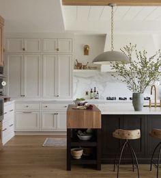 a kitchen with two stools in front of an island