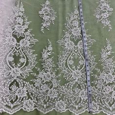 Let the beauty of our Beaded & Corded lace fabric lift the elegance of any special occasion. Made from 100% Polyester Net Mesh, this beautiful fabric is lovingly embroidered with pearls and sequins. It is the perfect choice for wedding dresses, evening gowns, quinceanera dresses, dance costumes, and more. Our collection of Beaded and Corded couture lace and bridal lace, has something for every woman who wants to look her best. Whether it's for a special occasion or for a momentous evening, our f Festive Pearl Embroidered Lace Fabric, Off-white Embroidered Lace Fabric For Wedding, White Lace Embroidered Fabric With Sequins, White Beaded Lace Embroidered Fabric, Silver Embroidered Lace Sequin Fabric, Quinceanera Crown, Corded Lace Fabric, Holiday Hours, Bridal Lace Fabric