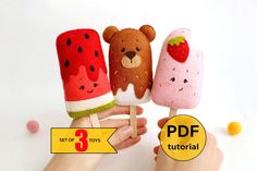 hand holding three popsicles with different designs on them