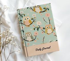 a notebook with an owl pattern on it next to flowers and baby's breath