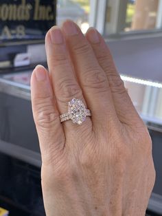 a woman's hand holding a diamond ring in front of a store display case