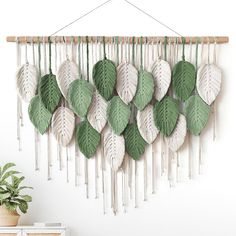 a green and white wall hanging with leaves