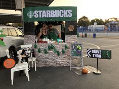 a man and woman standing behind a starbucks stand