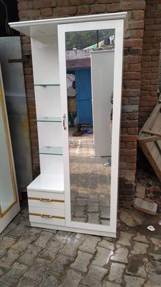 a white cabinet sitting on top of a brick floor next to a wall with glass doors