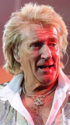 an older man with blonde hair and piercings on his neck is making a face