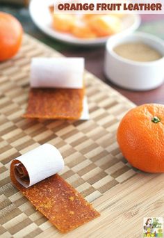 an orange sitting on top of a wooden cutting board next to a roll of paper