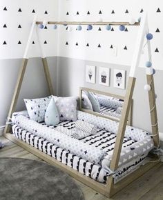 a child's swing bed in a white room with black and blue decorations on the walls