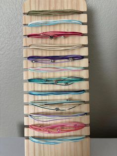 a wooden rack with many different colored threads on the top and bottom of it