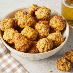 a bowl filled with meatballs next to a cup of sauce