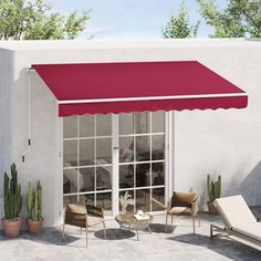 a red awning on top of a white building next to a patio with chaise lounges