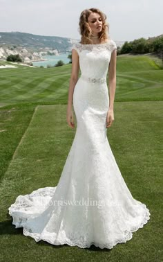 a woman standing on top of a lush green field wearing a white wedding dress with an open back