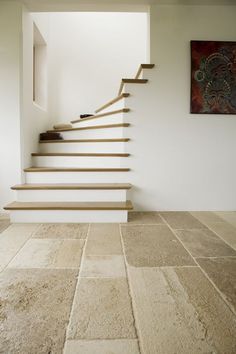 a set of stairs leading up to the second floor in a house with white walls and stone floors