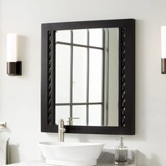 a white sink sitting under a bathroom mirror next to a wall mounted faucet