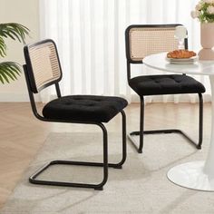 a white table with two black chairs and a potted plant on top of it