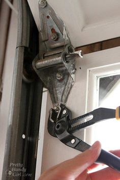 a person is holding some pliers in front of a door handle and window frame