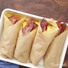 four wrapped breakfast burritos in a white dish