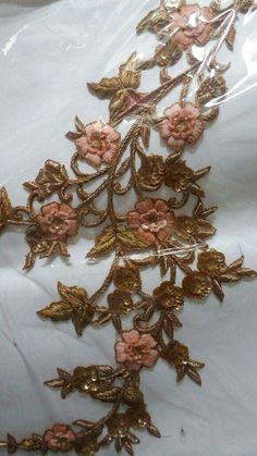 some pink flowers and gold leaves on a white sheet