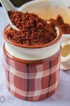 a spoon is in a jar filled with ground cinnamon and some other things on the table