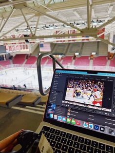 an open laptop computer sitting on top of a table in front of a hockey rink