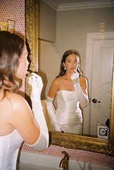 a woman brushing her teeth in front of a mirror while looking at herself in the mirror