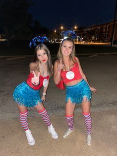 two young women dressed in cheerleader outfits posing for the camera with their thumbs up