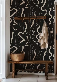 a wooden bench sitting in front of a wall with black and white designs on it