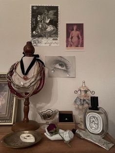 an assortment of jewelry on a table with pictures and other items in front of it