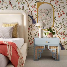 a bedroom with wallpaper and a pink dresser next to a bed in front of a mirror