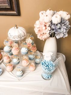 a table topped with cupcakes and candy next to a vase filled with flowers