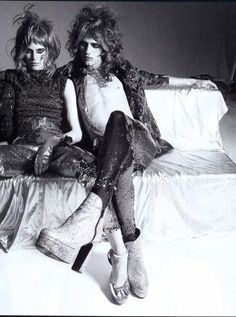 two women sitting on top of a bed next to each other in black and white