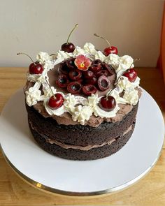 a chocolate cake topped with cherries and whipped cream