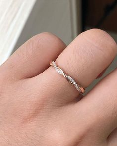 a person's hand with a gold and white diamond ring on their left finger