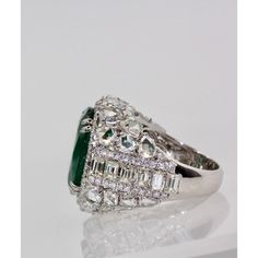 This is part of Chairish’s Fine Jewelry assortment.  Oval Emerald 12.25 Carat Diamond Surround 8.85 Carat Total Weight 21.10 Carat  This oval Emerald weights in at 12.25 carats and is a gorgeous Emerald Green with transparency. The Diamonds weigh in at 8.85 Carats and the mount is exceptional the Diamonds are VS1-VS2 and G-J in color. This is a bombe mount. The shoulders of the ring are embellished with baguette cut Diamonds in the center border with a perimeter of round cut Diamonds accents. Th Luxury Green Marquise Diamond Ring, Luxury Green Diamond Ring In Platinum, Luxury Gia Certified Pear-shaped Wedding Ring, Luxury Diamond Cluster Ring With Gemstones, Luxury Pear-shaped Diamond Ring With 17 Jewels, Luxury Marquise Emerald Ring For Wedding, Luxury Marquise Emerald Wedding Ring, Luxury Green Diamond Ring For Formal Occasions, Dazzling Green Diamond Ring For Formal Occasions