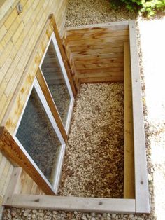 an open window on the side of a brick building next to gravel and grass area