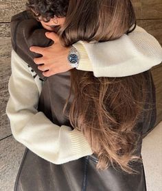 a woman with long hair is hugging another woman's head in front of a wall