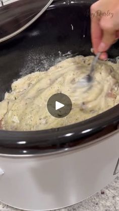 a person stirring food in a slow cooker