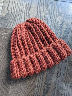 a red knitted hat laying on top of a wooden floor