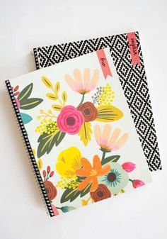 two notebooks with floral designs on them sitting next to each other, one has a black and white chevron background