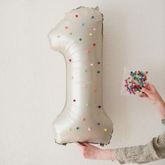 a person holding a large balloon with sprinkles on it and a bag of candy