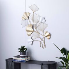 a black table topped with a plant next to a wall mounted metal art piece on top of a white wall