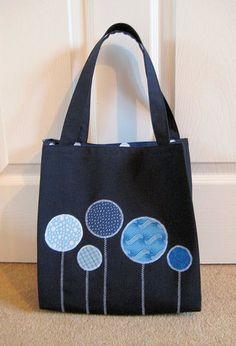 a black bag with blue flowers on it sitting in front of a white door handle