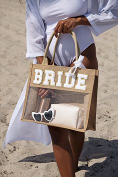 a woman is walking on the beach carrying a handbag that says,'bride '