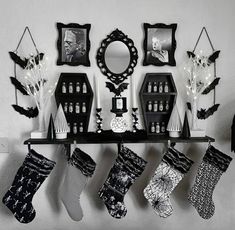 black and white christmas stockings hanging on a shelf in front of a mirror, framed pictures, and other decorations