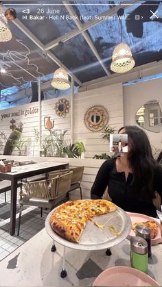 a woman sitting at a table with a pizza in front of her and another person taking a photo